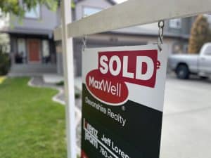 Sold Sign on a lawn with a grey house in the background